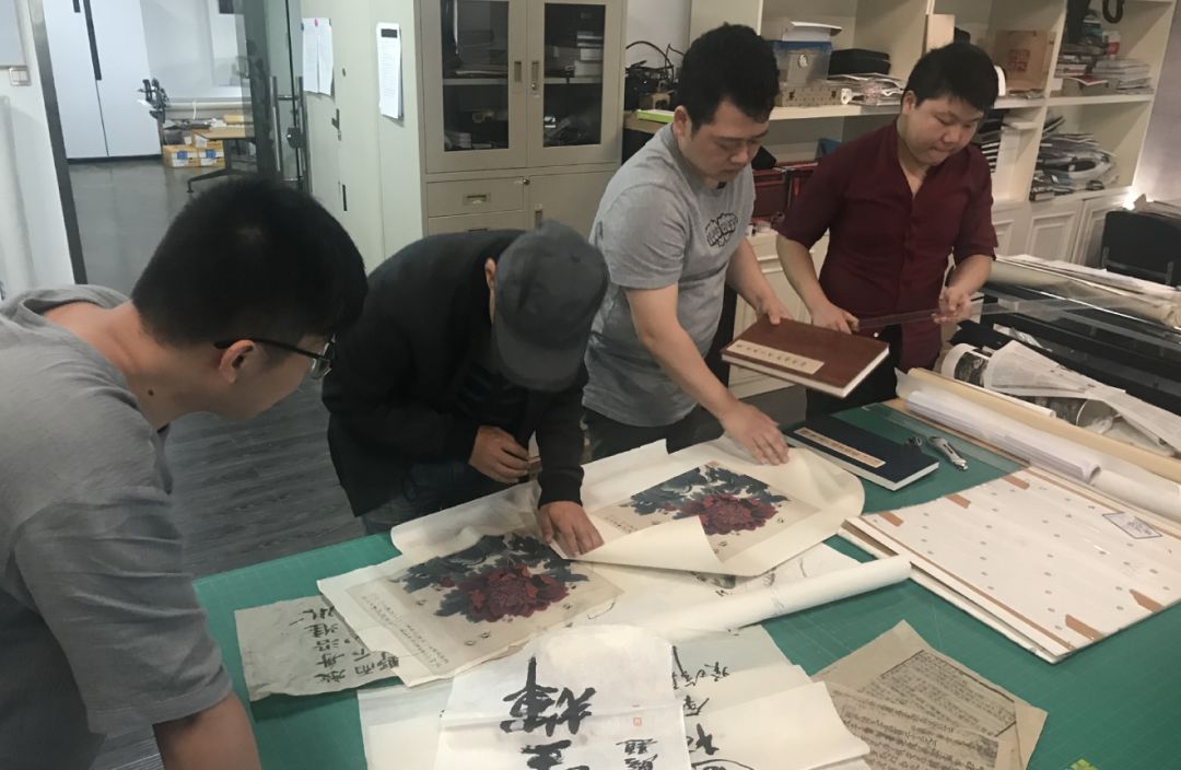 多人在桌旁审查字画与书页